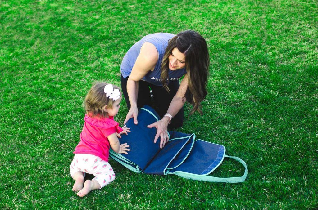 mom folding baby picnic blanket with her toddler