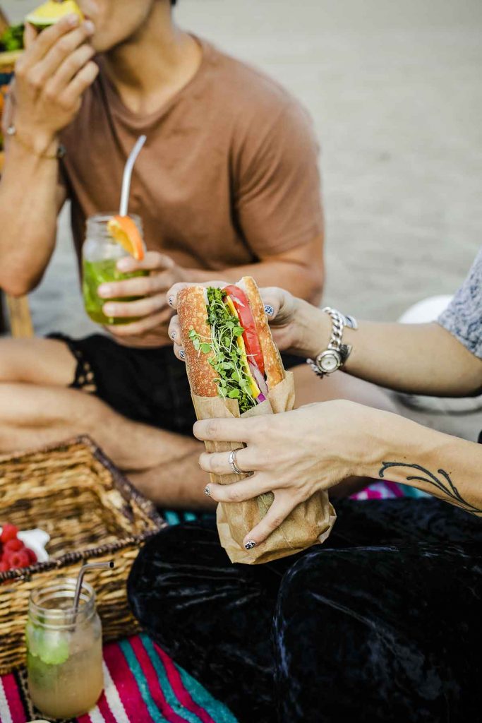 woman holding a sandwich wrapped in paper at picnic