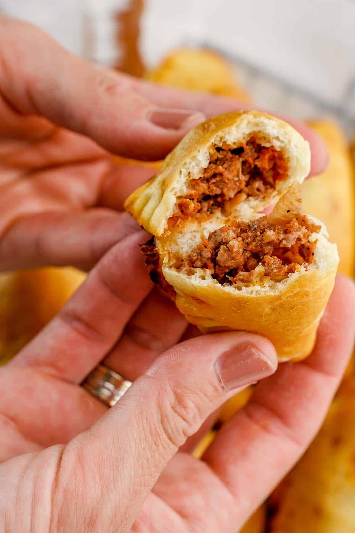 hand holding Beef Empanadas open to expose the filling
