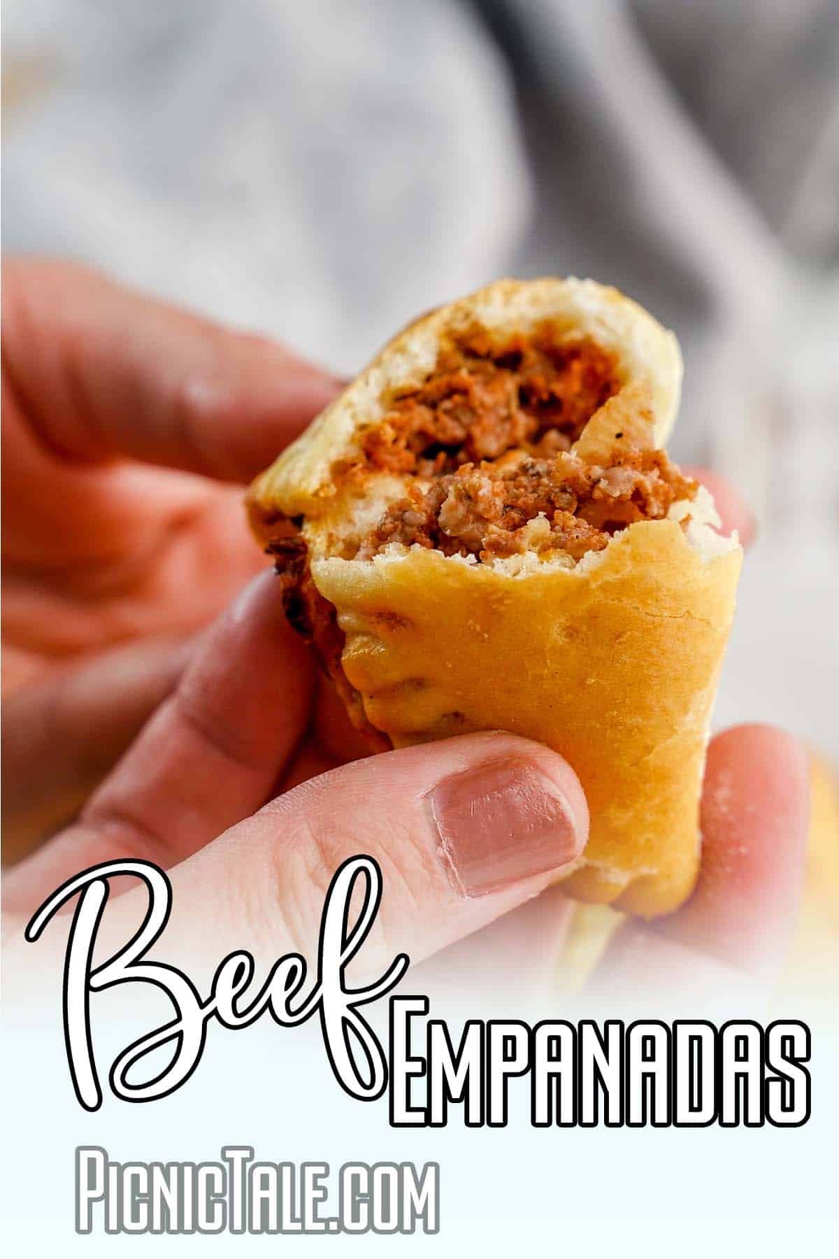 hands holding empanadas to show the filling with text which reads beef empanadas