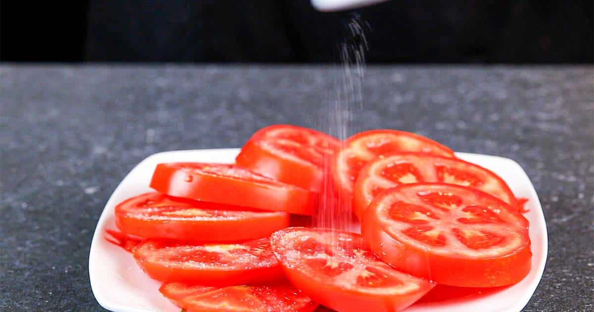 seasoning tomatoes to make a Caprese Salad