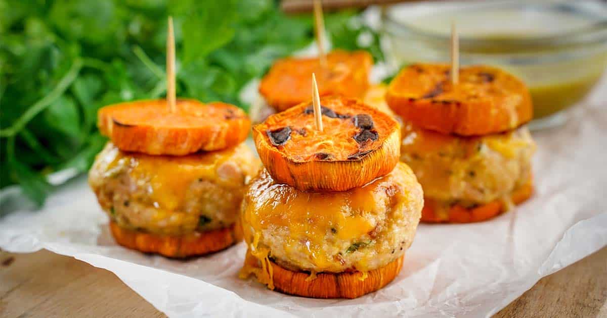 Four Stacked Turkey Sliders with Sweet Potato, on Paper with bowl and parsley in background.
