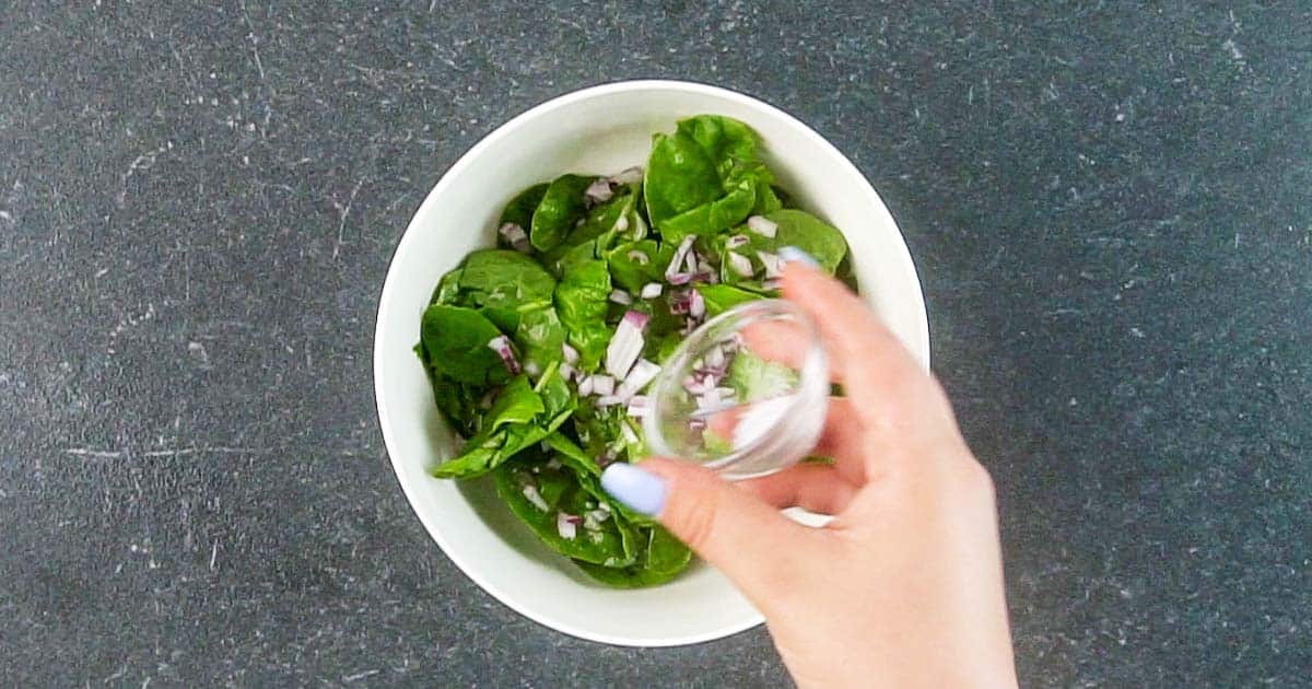 adding dressing to make Wilted Spinach Greens