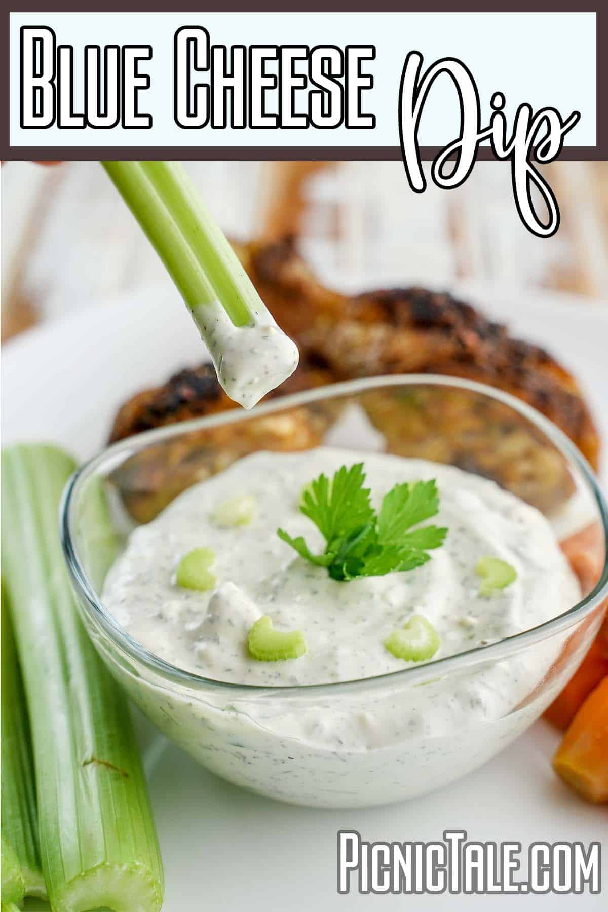 dipping a celery stalk into a bowl of blue cheese dip with text which reads blue cheese dip