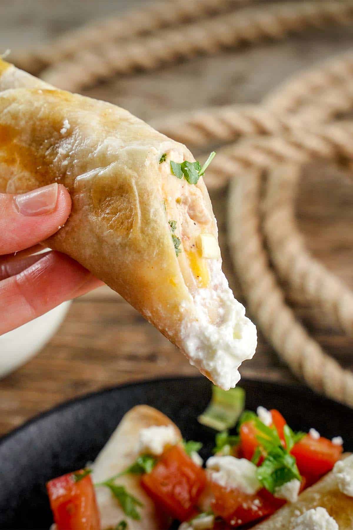 chicken taquitos being dipped in sour cream