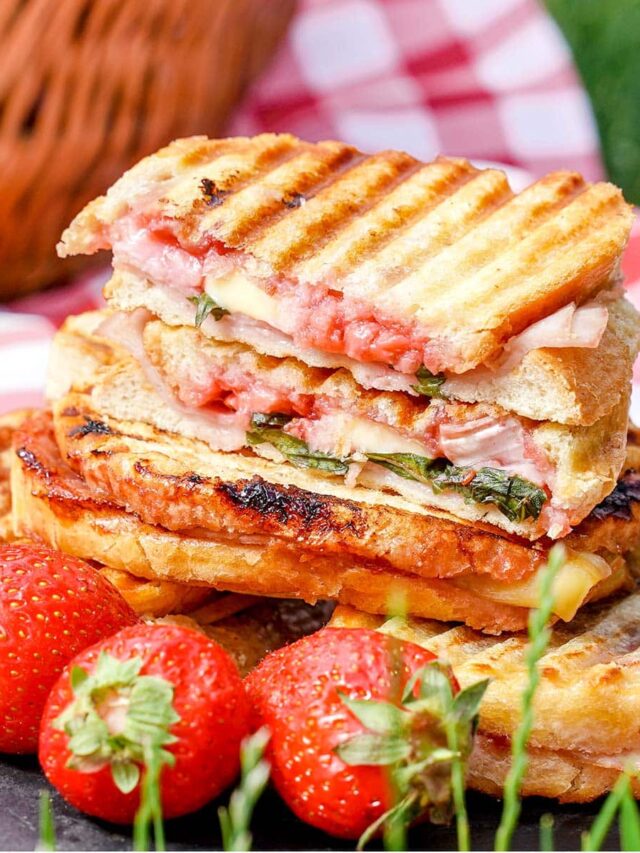 Brie grilled cheese sandwich, strawberries in front of stack.