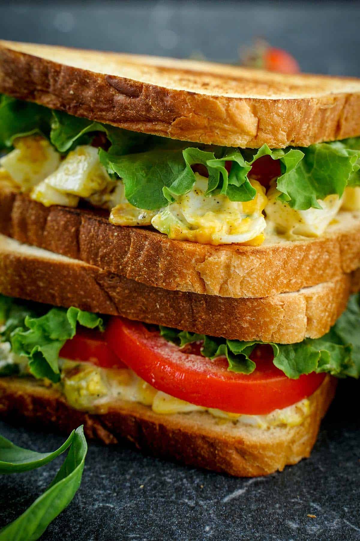 Stack of two Egg salad sandwich, on slate.