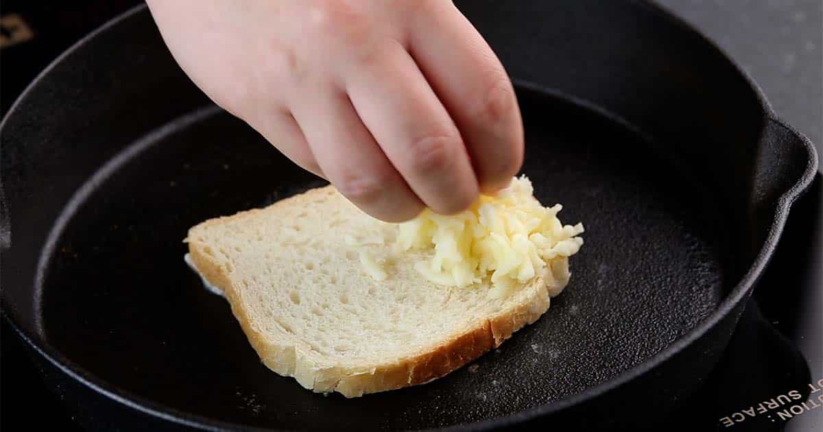 cheese being added to bread to make a greek grilled cheese sandwich