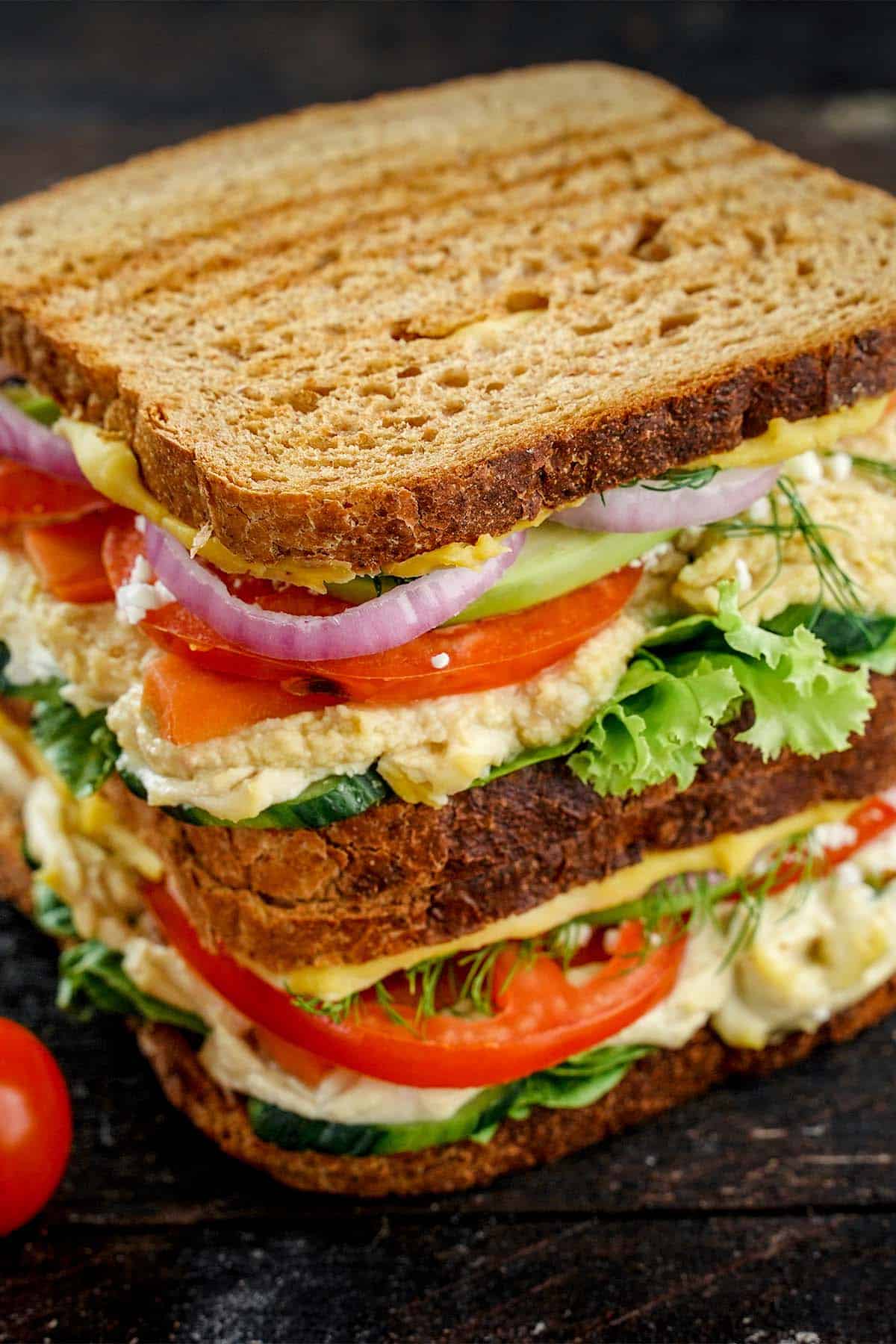 Close up of hummus sandwich on black base.