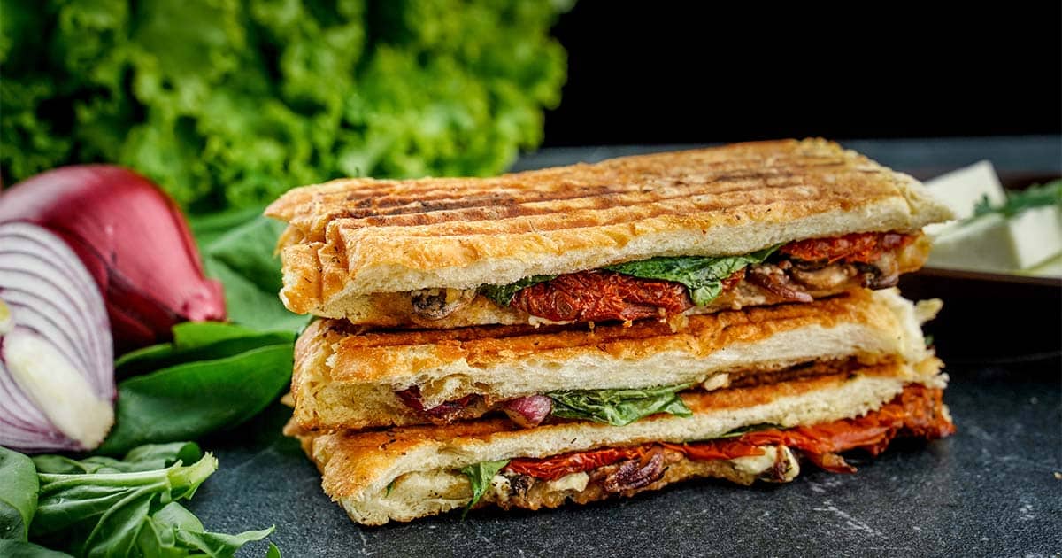 Stacked Mushroom Panini sandwich, with onion and basil leaves.