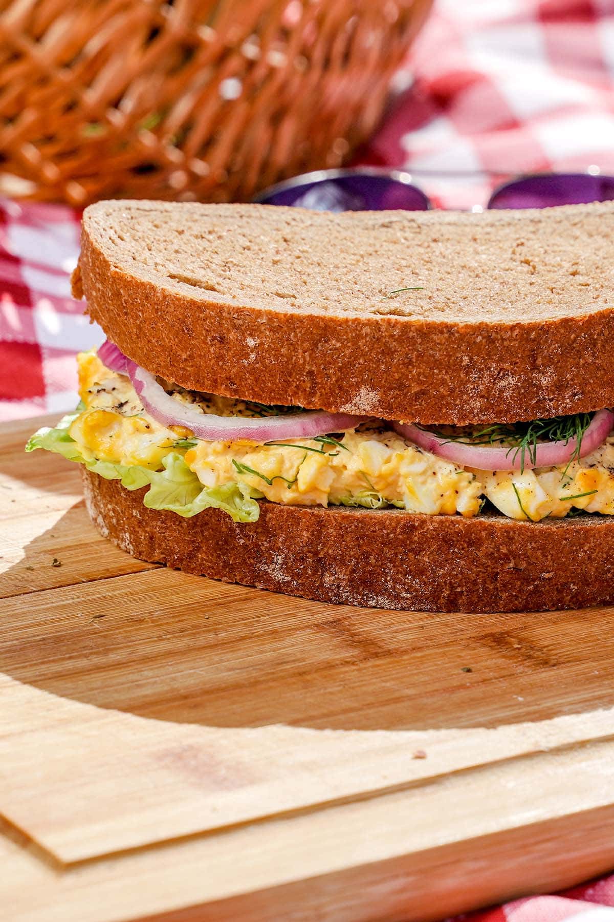 Ultimate egg salad sandwich, on cutting board with shadow.