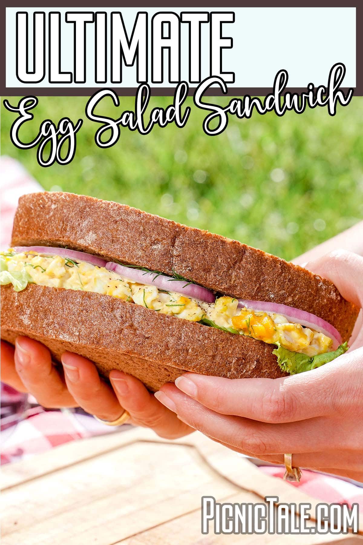 Ultimate egg salad sandwich, held outside with lettering at the top.